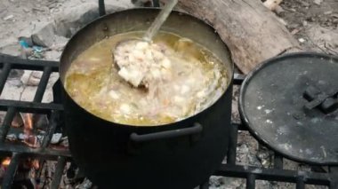 Bir kepçe ile bir el kaynar çorba içinde malzemeyi karıştırır. Doğada büyük bir tencerede pişirme. Yürüyüş yolcuları için yiyecek. Kamp turistleri. Close.