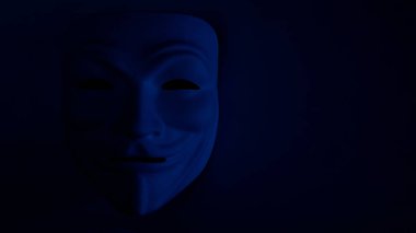 Mavi koyu bir arka plan üzerinde kötü görünür maske. İsimsiz bir hacker ya da cadılar bayramı partisi sembolü. Kopya alanı. Karanlık bir anahtarla bir deneği vurmak. Masaüstü duvar kağıdını izleyin. Film tanesinin etkisi.