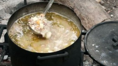 Doğal, turizm, dağlar kavramı- Bowler kazık. Su ısıtıcısı yanıyor, kampta yemek pişiriyorum. Güzel lezzetli çorba ateşte büyük bir tencerede kaynar.