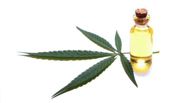 Close-up. A leaf of young marijuana and a bottle of oil, closed by a cork. Industrial processing wild hemp or legalization of medical cannabis. White background. — Stock Photo, Image