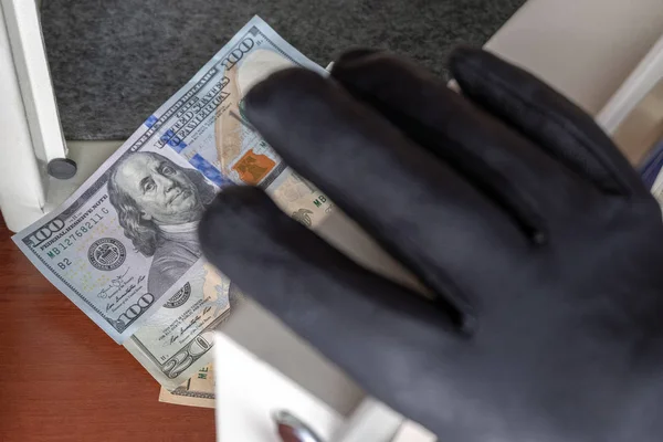 A black-gloved thief opens the safe door with a combination lock. Security at home, hotel and office. Theft of valuables and money. Selective focus. Shallow depth of field.