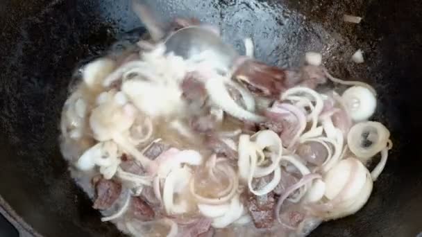 요리사는 고기가 기름에 양파와 튀겨지는 가마솥의 뚜껑을 엽니다 필라프 굴라쉬를 — 비디오