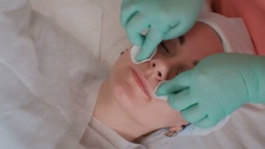 Güzellik uzmanı pamuk pedli güzel bir kızın yüzünü siler. Bir güzellik salonunda Avrupalı genç kadın. Sağlık ve gençlik. Spa'da anti-aging tedavisi. Cilt bakımı ve kırışıklık tedavisi.