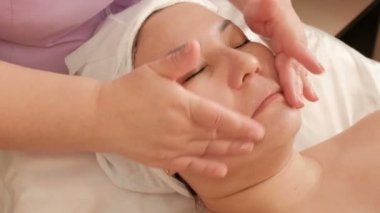 Yüz masajı. Kadın cilt bakımı. Bir güzellik salonunda Asyalı kız. Sağlık ve gençlik. Spa'da anti-aging tedavisi.