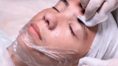 Güzellik uzmanı genç bir çocuğun alnına sivilce sıkıyor. Güzellik kliniğinde beyaz eldivenli ellerin kapatılması. Erkek müşteri yüz kozmetoloji prosedürü alır. Tıbbi yüz cilt temizliği.