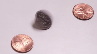 Küçük Amerikan sikkeleri masada döner. Çeyrek dolar, bir kuruş ve beyaz bir arka plan için iki sent. Bankacılık ve finansal kriz veya servet birikimi teması.