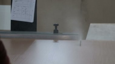 Mobilya imalatı. Yonga levha dairesel testere ile bir makine üzerinde testere. İşçi bir kesme kartı ile yönlendirilir. Genel plan. Ahşap atölyesi. Testere makinesinin orijinal sesi.