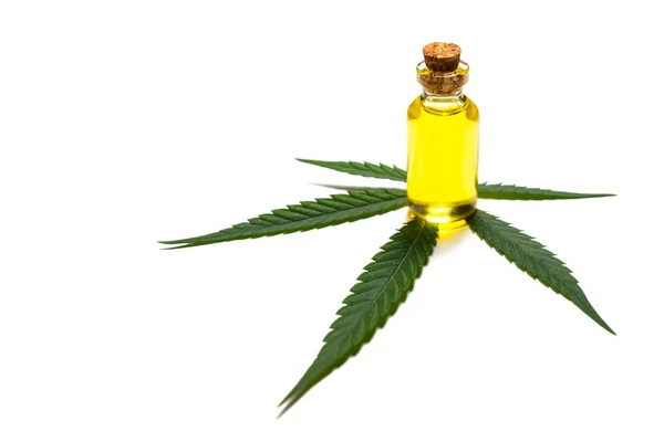 A bottle of yellow oil stands on a leaf of green cannabis. The concept of legalization or medical use of marijuana. Useful properties of hemp. — Stock Photo, Image