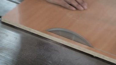 Makinede dairesel testereolan bir adam tahta bir çarşafın kenarını keser. Close. Parçacık tahtası testere dükkanı. Mobilya imalatı.