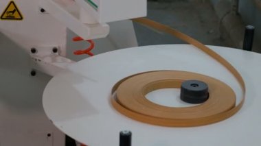Kenar yonga levha parçaları için makine. Mobilya detayları yapıştırma için kahverengi kenar bir rulo hareketi. Çalışan bir ahşap işleme makinesinin gerçek sesi.