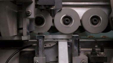 Mobilya imalatında Pvc kenarların otomatik yapıştırma ve chamfering. Kenar bantlama makinesinin ters tarafı. Tekerlekler üzerinde yonga levha rulo parçası.
