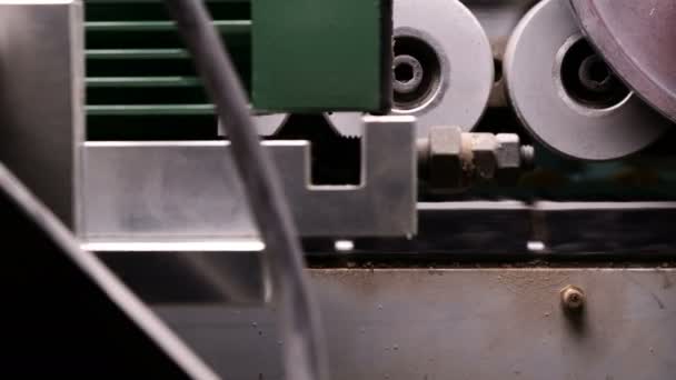 Het interne mechanisme van de rand banding machine. Onderdeel van spaanplaat rollen op wielen. Automatisch lijmen en snijden van PVC-randen in meubelproductie. — Stockvideo