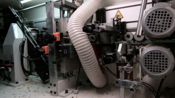 Widok ogólny odwrotnej strony Okleiniarka. Automatyczne klejenie, przycinanie krawędzi PVC i fazowanie części płyt wiórowych w produkcji mebli. Rolki z płyt wiórowych na rolkach. — Wideo stockowe