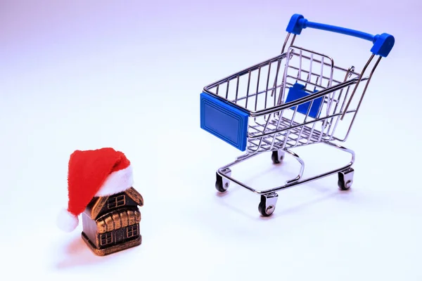 산타 클로스 모자와 쇼핑 카트와 기념품 집. 새해 할인, 크리스마스 놀라움, 집들이 또는 새 집을 구입. 개념. 카피 스파. — 스톡 사진