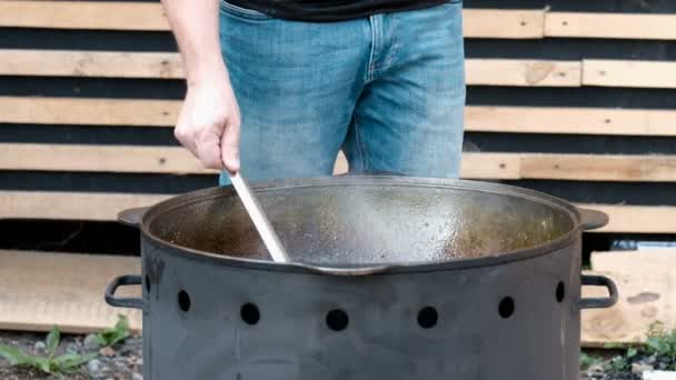 Homem Jeans Está Cozinhar Num Caldeirão Ferro Fundido Livre Mexendo — Vídeo de Stock