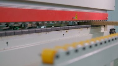 Kenarları yonga levha parçalarına yapıştırmak için makine. Mobilya imalatı. Sığ alan derinliği, seçici odak. Makinedeki silindirlerin otomatik hareket mekanizması.