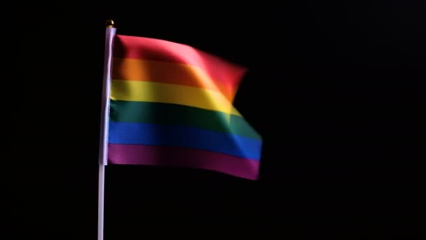 黒い背景にLgbtフラグ 性的マイノリティの概念 虹のプライドフラグが風に揺れ始めます 同性の人々の間の独立と愛の象徴 — ストック動画