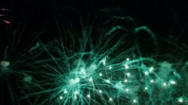 Siyah bir arka plan üzerinde yakın çekim yeşil, kırmızı ve altın şenlikli havai fişek. Soyut tatil arka planı