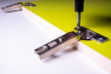 Tornavida ile vida sıkma. Yonga levhadan yapılmış yeşil bir kapı üzerine kapılar için mobilya gölgelik montajı. Close. Mobilya parçalarının üretimi, montajı ve satışı konsepti.