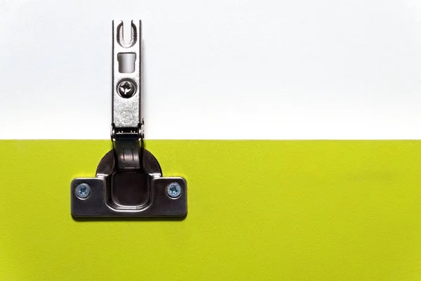 Meubilair scharnier voor deuren gemonteerd op een groene plaat van spaanplaat. Kopieer ruimte. Close-up. Het concept van productie, installatie en verkoop van meubelbeslag. — Stockfoto