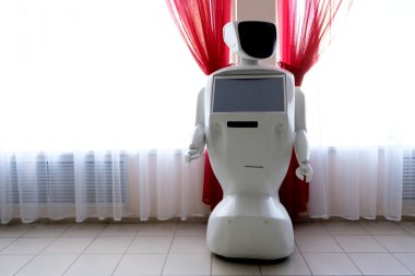 Bilgi robotu. Silah yerine manipülatörleri olan insansı bir makine ve göğsünde bir ekran kırmızı perdeleri olan bir pencerenin yanında duruyor. Yapay zekalı asistan ve defans oyuncusu. Copyspace