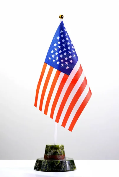 Asztali amerikai zászló egy kőállványon egy fehér asztalon. A tisztviselők vagy üzletemberek hivatalos találkozójának koncepciója. — Stock Fotó