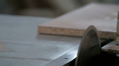 Machine with a circular saw. Sawing parts from chipboard. Furniture manufacture. A close-up of the worker s hands pushing the sawn part aside. Safety precautions. Real sound.