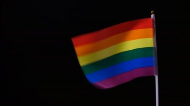 A rainbow flag sways in the wind. LGBT Conceptual. Advocacy of sexual independence and freedom of relationship and love.The concept of sexual minorities. Black background.