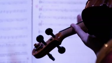 Kemancı. Yakın plan. Kemancının boynundaki kadın eli bir nota kağıdında. Arkadan bak. El kamerasıyla çekilirken kamera hareketi. Müzik konseri ya da parti.