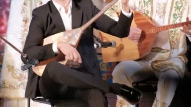 Kazakistan müziği. Erkek müzisyenler dombra çalar. Kazak ulusal müzik aletleri ve giysileri. Konser performansı.