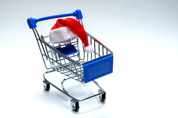 Santa Claus hat on a shopping trolley. Christmas and New Year discount concept, online, consumer basket level, black friday and holiday sale. Copy space.