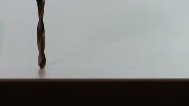 Yakından ahşap delme. Matkap yonga tahtasına çarpar ve mobilya vidaları için bir delik açılır. Uzayı kopyala Mutfak ya da ofis seti hazırlıyorum. Siluet ve gölge.