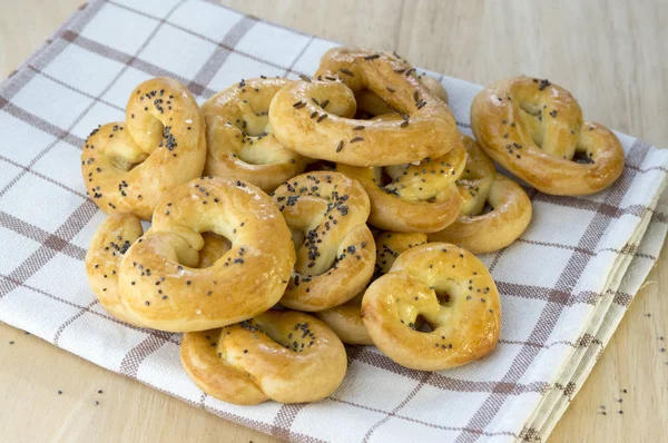 Havlu, kalp ve bükülmüş düğüm şekilleri, ahşap masa üzerinde pişmiş taze simit haşhaş tohumu tuz ve kimyon tohumu ile kaplı