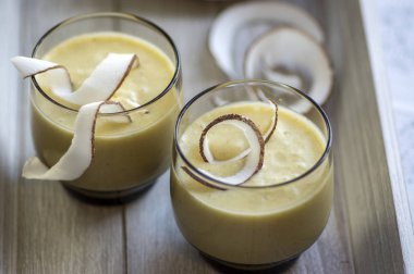 Ananas smoothie muz, oatmeals ve Hindistan cevizi sütü ile dekore edilmiş ile Hindistan cevizi cips, ahşap kahvaltı tepsisi