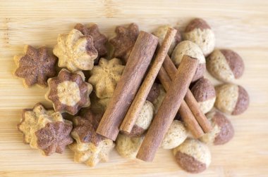 Tarçın sandbakelse Noel kurabiyeleri, iki renkli, koyu kahverengi kakao ve vanilya altın kahverengi, tarçın ham kabuk baharat, yıldız ve fındık şekiller üzerinde ahşap arka plan ışık