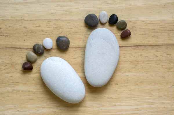 Two tiny stone feet and ten toes on wooden background, stone in the shape of a human feet