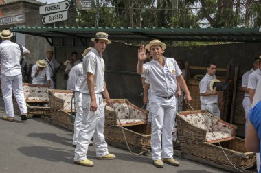 Monte, Funchal / Madeira - 22 Nisan 2017: erkekler geleneksel beyaz üniforma, saman boaters ve sepet arabalar yokuş aşağı ziyaretçilerinden Monte taşıma ile