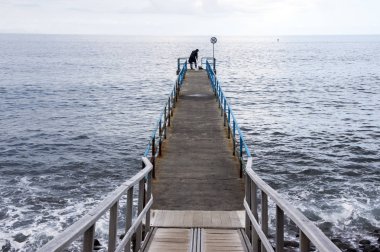 Balıkçı siluet ucunda, vahşi okyanus dalgaları, Funchal, Madeira, Portekiz ile ile ahşap bağlantı noktası pier