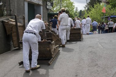Monte, Funchal / Madeira - 22 Nisan 2017: erkekler geleneksel beyaz üniforma, saman boaters ve sepet arabalar yokuş aşağı ziyaretçilerinden Monte taşıma ile