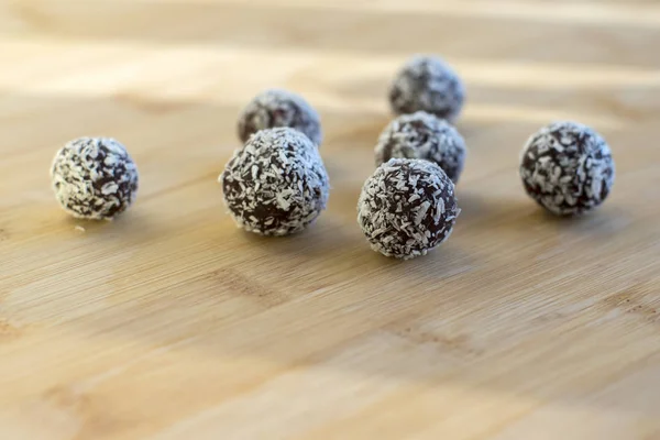 chocolate coconut balls decorated with shredded coconut on wooden bamboo table
