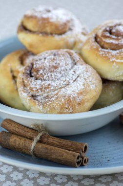 Tarçın salyangoz kanelbullar denilen, çok lezzetli tatlı mavi kapta rulo çiçek desenli masa örtüsü, lezzetli bisküviler, ham tarçın