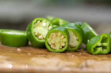 Capsicum annuum Jalapeno biber biber, yeşil grup dilimlenmiş meyve tohumları, Meksika mutfağı ile ahşap kesme tahtası üzerinde