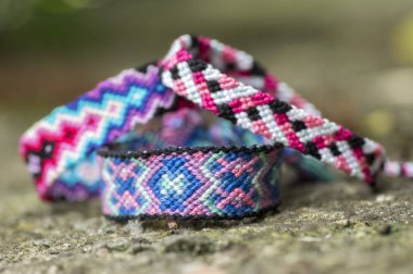 Üç el yapımı ev yapımı renkli doğal dokuma gri taş arka plan üzerinde ayrıntı görünümü izole dostluk bilezik