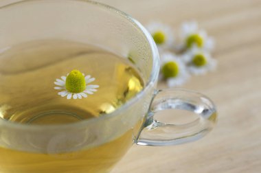 Matricaria chamomilla çiçekler ve ahşap masa, cam kupa bitkisel ilaç çiçekli taze çay fincan trasparent