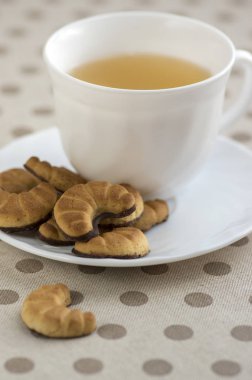 Bisküvi lezzetli çikolata tatlılar çay molası, beyaz küçük Kupası beyaz plaka üzerinde rulo