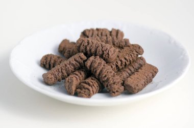 Koyu kahverengi kakao çay ışık arka plan üzerinde izole bisküvi beyaz tabakta lezzetli sağlıksız tatlılar,