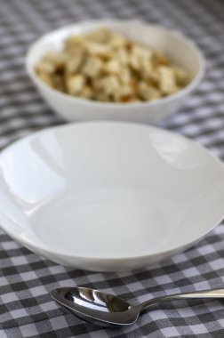 Altın taze pişmiş ekmek çorbası için boş beyaz tabak tereyağı, beyaz plaka ve gri kareli masa örtüsü küpler halinde kesilmiş