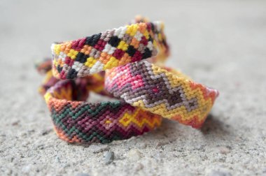 Üç basit el yapımı ev yapımı doğal dokuma dostluk bilezik gri beton arka plan, gökkuşağı renkleri, Damalı deseni