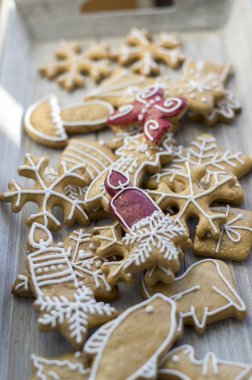 Yaz, tatil için ortak lezzetli tatlılar, çeşitli şekiller içinde ahşap tepsi üzerinde düzenlenen geleneksel Noel gingerbreads boyalı, kar taneleri, mumlar ve yıldız, beyaz şeker buzlanma boyama, kırmızı renk