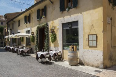 Verona dar sokak boş yaz sezonu, konuklar, gölge ve güneş ışığı ile Restoran